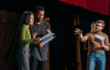 Director and actors rehearse on theatre stage